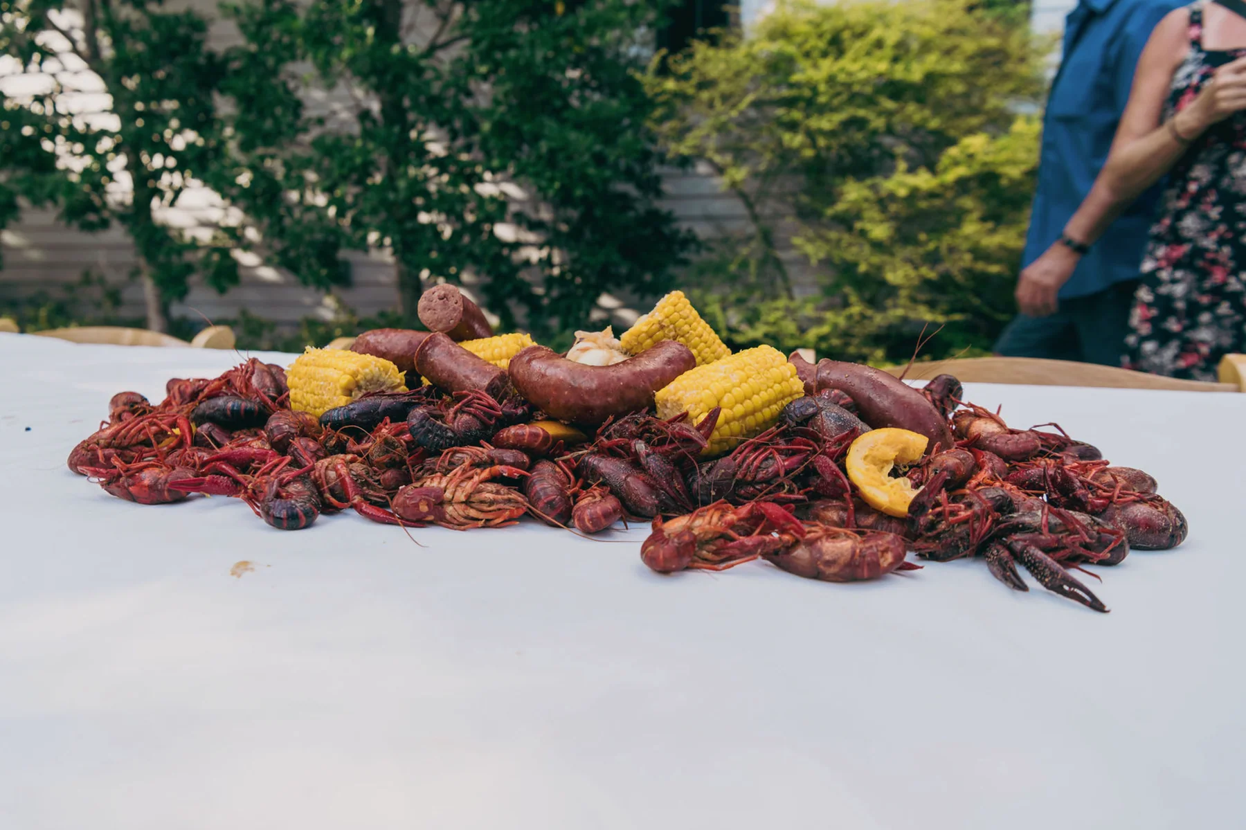 Crawfish, sausage, corn, and lemons on an outdoor table